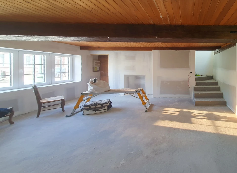 Salon moderne sous combles avec canapé blanc, tables basses rondes noires et télévision murale