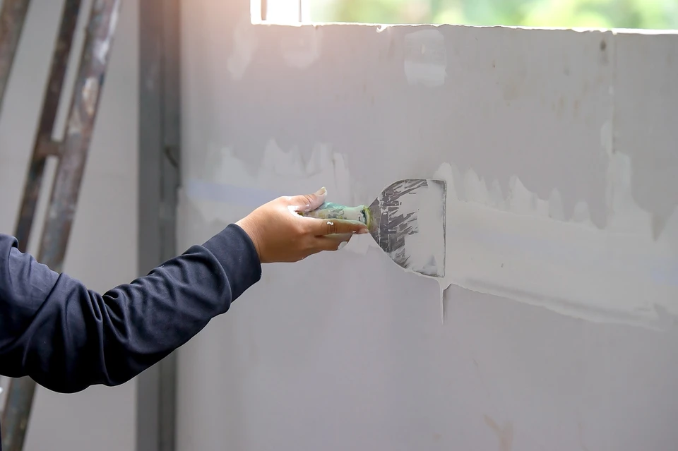 Homme en vêtement de travail traçant une ligne au crayon sur carrelage blanc moucheté, utilisant une règle comme guide