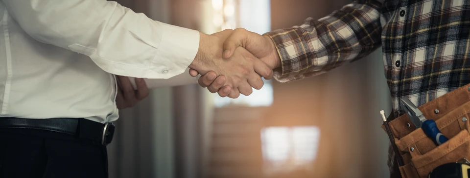 Trois professionnels examinent des plans architecturaux autour d'une maquette urbaine détaillée avec arbres miniatures et bâtiments