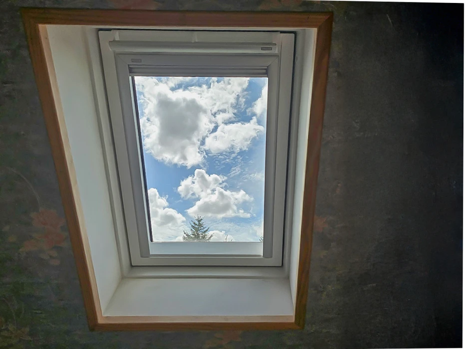 Intérieur en cours de finition avec cloisons sèches non peintes, plafond mansardé avec poutres apparentes blanches